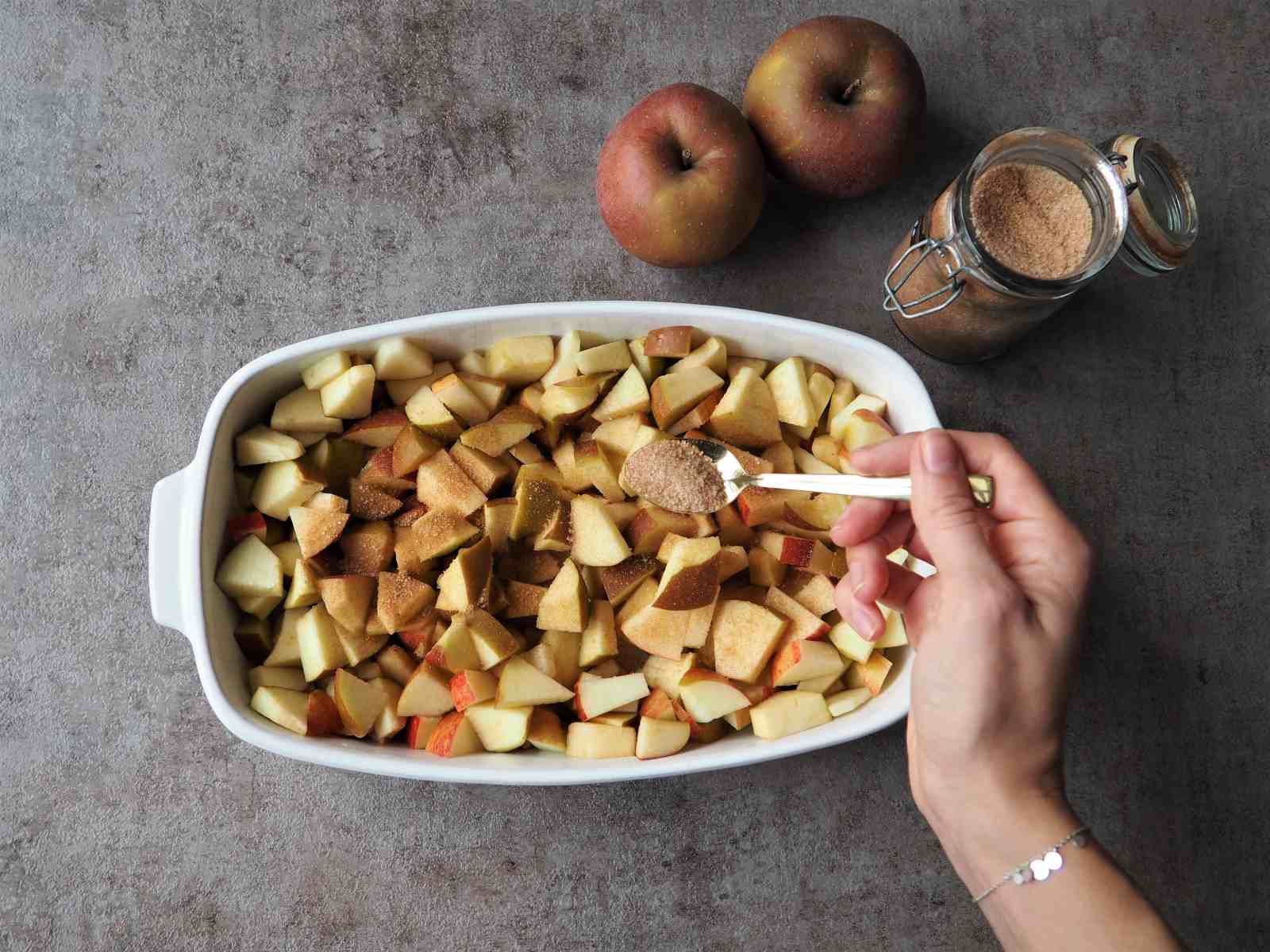 Gewürfelte Äpfel werden in Auflaufform mit Zimt-Zucker bestreut