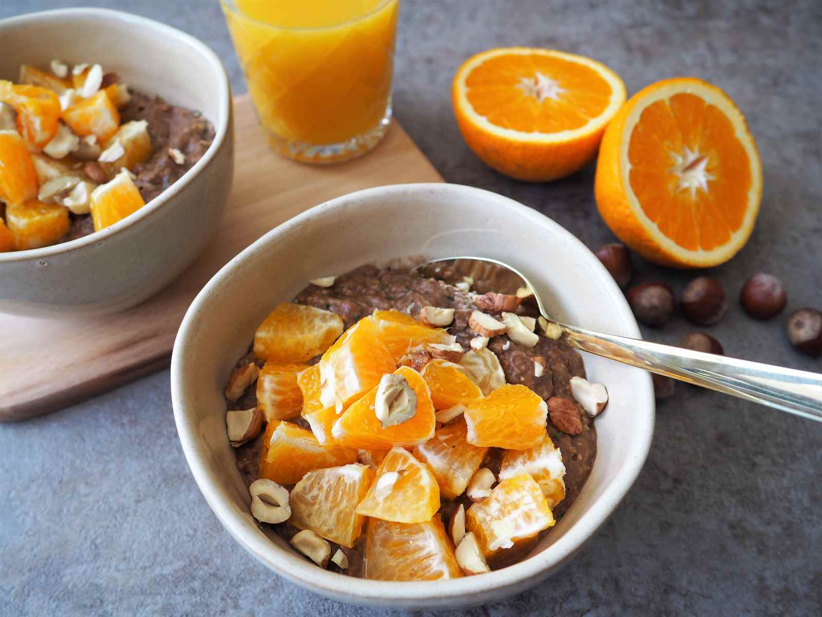 Schokoladiges Zucchini-Orangen-Porridge angerichtet mit Nüssen und Orangensaft